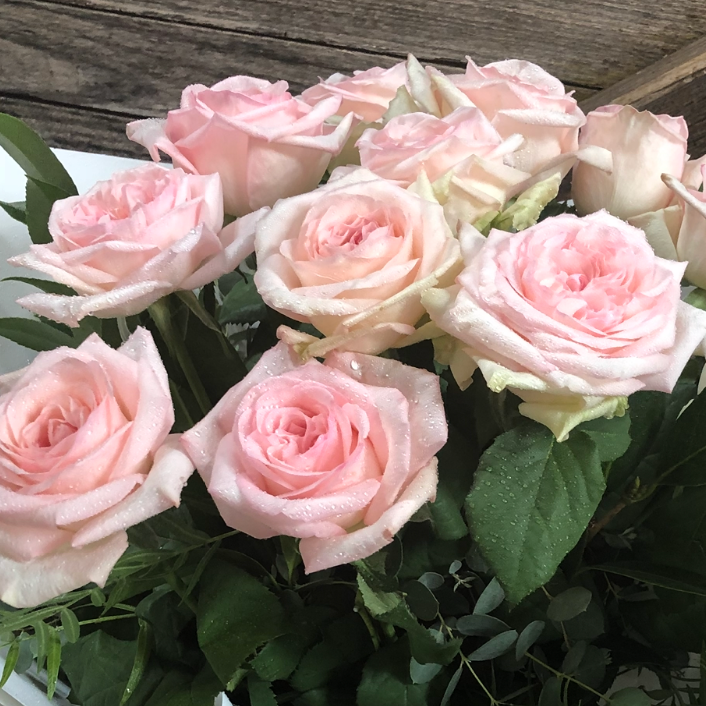 Bouquet of pink roses wrapped in paper on a wooden surface with a timestamp at the top.